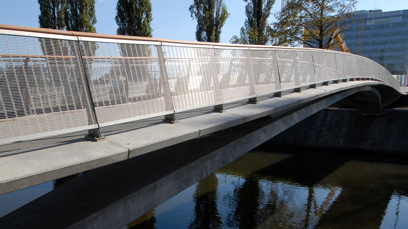 Bridge over a river with a stainless steel mesh bridge railing.