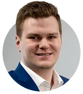 Porträtfoto von Herrn Wegner, Mitarbeiter bei Haver & Boecker, lächelnd, in blauem Anzug mit weißem Hemd, vor neutralem Hintergrund.