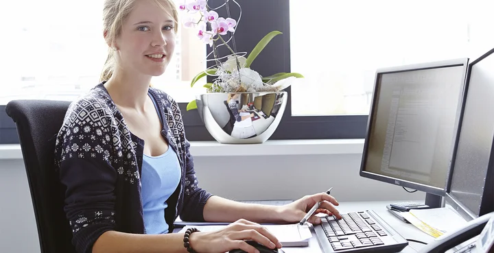 Eine Praktikantin sitzt an ihrem Arbeitsplatz im Büro.