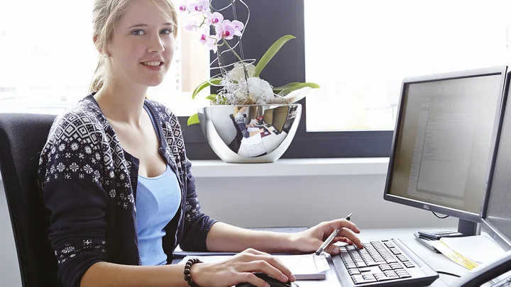 Eine Praktikantin sitzt an ihrem Arbeitsplatz im Büro.