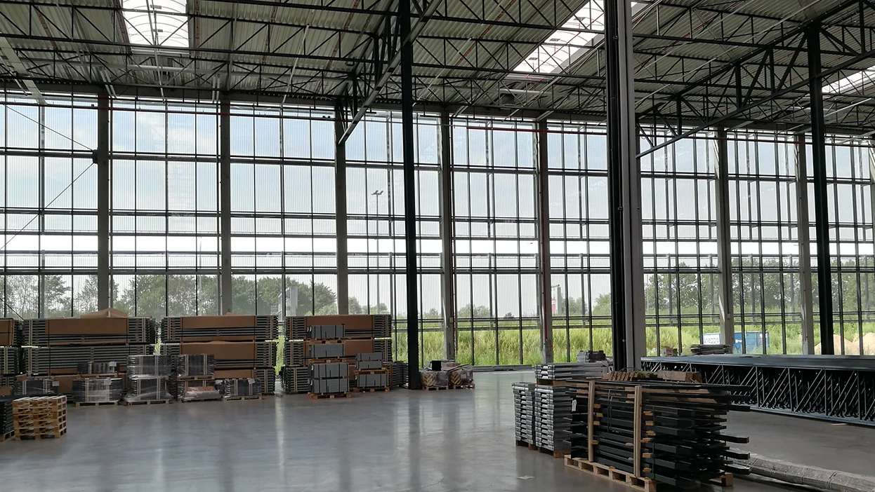 Innenansicht durch semitransparente Architekturgewebe-Fassade mit gutem Blick auf Felder und Himmel