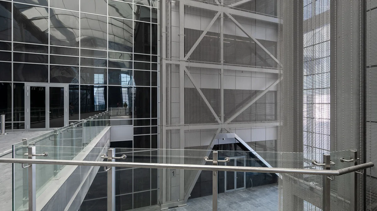 A view of a cross-storey wall covering made out of stainless steel wire mesh.