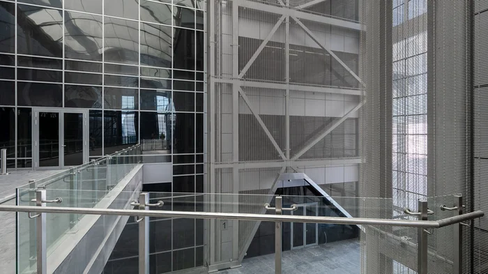 A view of a cross-storey wall covering made out of stainless steel wire mesh.