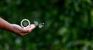 Hand mit digitalem CO₂-Abscheidungssymbol vor grünem Naturhintergrund als Symbol für nachhaltige Umwelttechnologie.