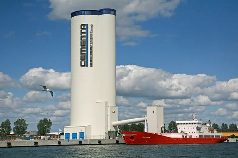 An einem Zementterminal mit einem Mehrkammersilo und Losebeladung für LKW und Waggons wird ein Zementschiff beladen.