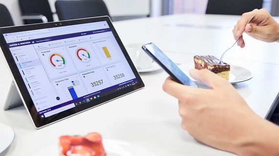 Person überwacht Anlagen-Leistungsdaten auf Handy und Tablet.