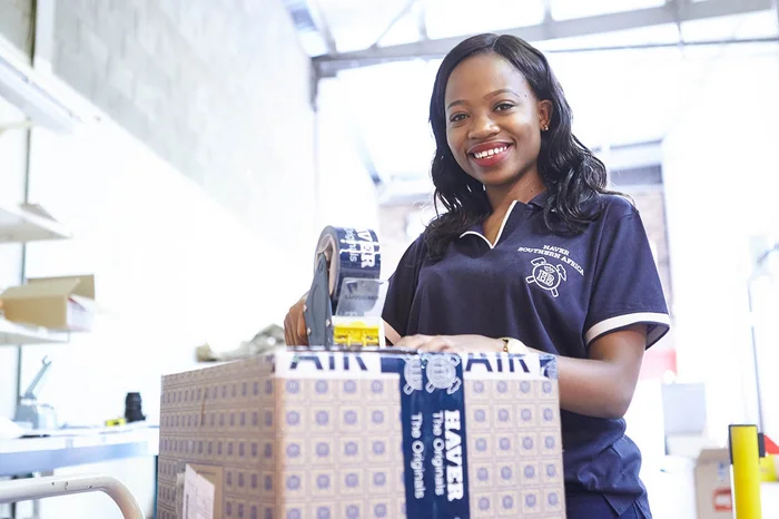 Mitarbeiterin von HAVER & BOECKER verschließt einen Karton mit Original-Ersatzteilen mit Klebeband.