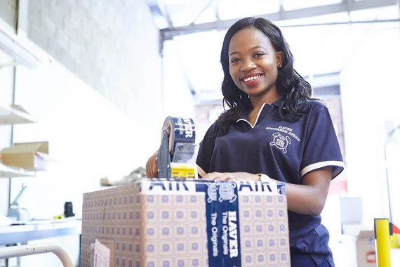 Mitarbeiterin von HAVER & BOECKER verschließt einen Karton mit Original-Ersatzteilen mit Klebeband.
