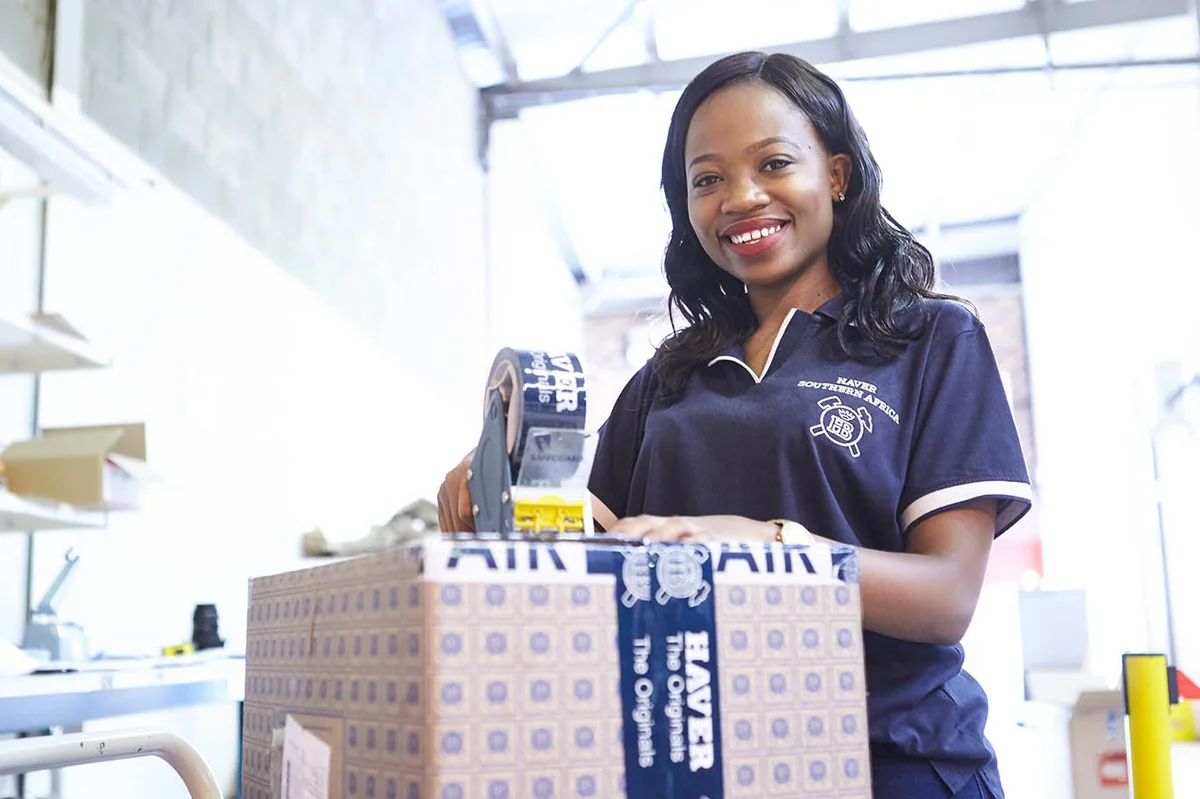 Mitarbeiterin von HAVER & BOECKER verschließt einen Karton mit Original-Ersatzteilen mit Klebeband.