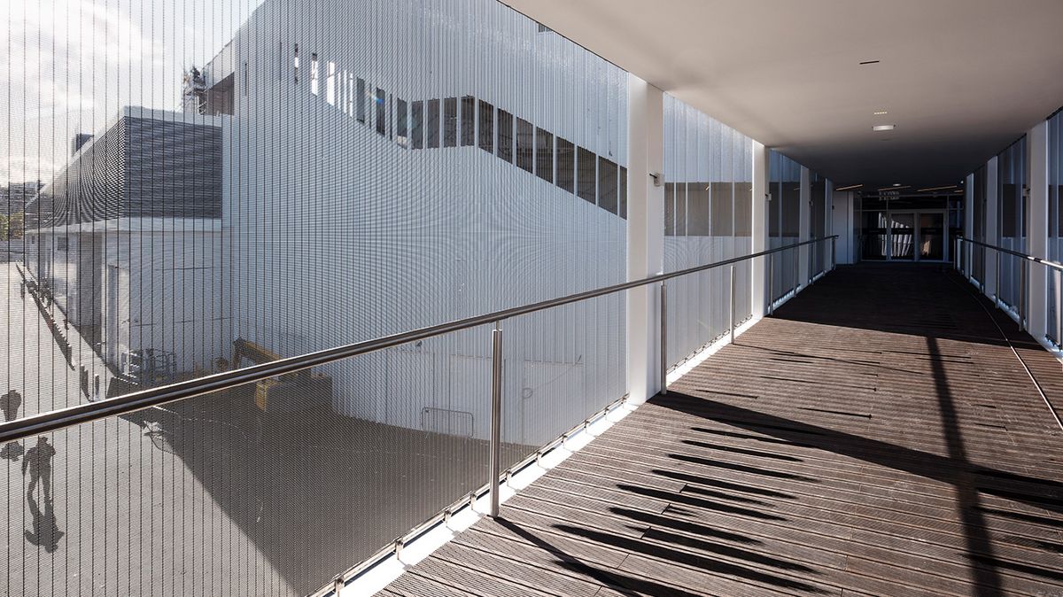 Cladding with wire mesh which functions as fall protection.