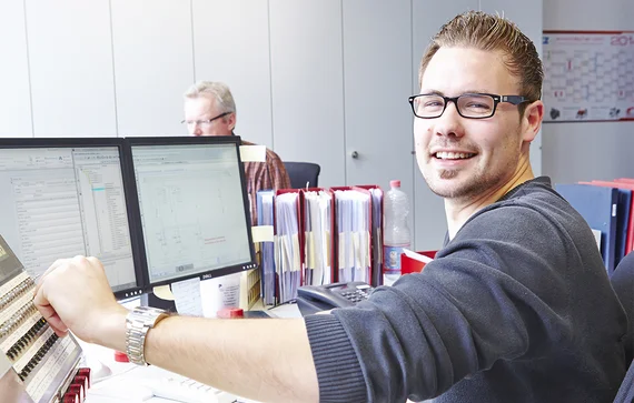 Ein Mitarbeiter sitzt an seinem Arbeitsplatz und bedient ein Gerät.