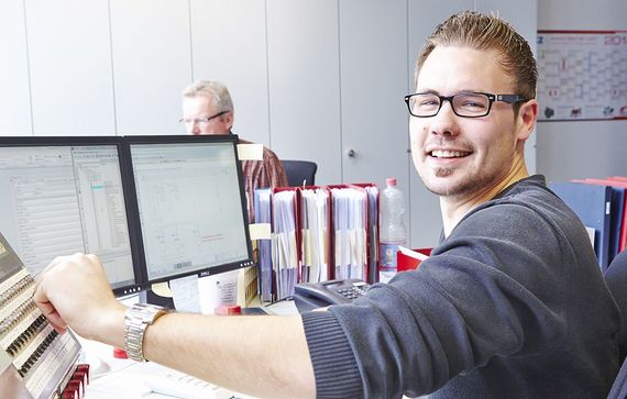 Ein Mitarbeiter sitzt an seinem Arbeitsplatz und bedient ein Gerät.