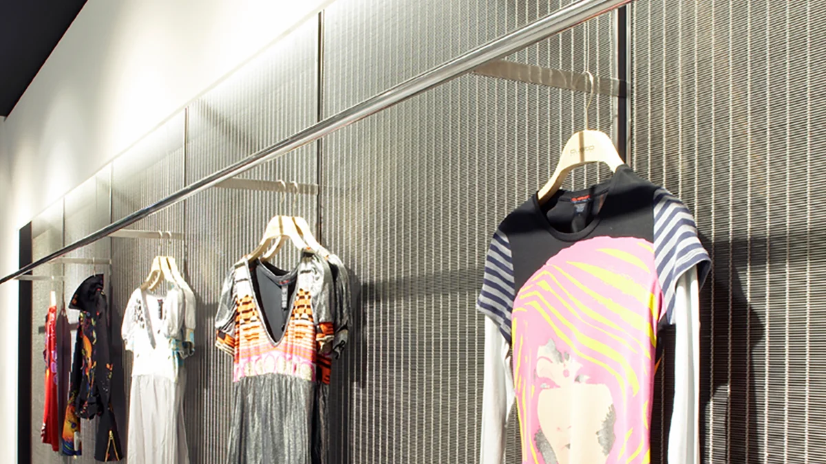 Conception de boutique : un revêtement mural de qualité en toile métallique pour sublimer les vêtements à vendre.