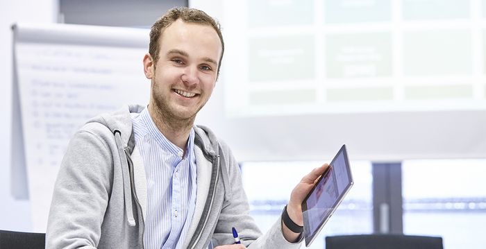 Ein angehender Industriekaufmann prüft Daten auf seinem Tablet.