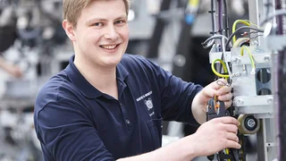 Ein Auszubildender arbeitet an  einer Maschine.
