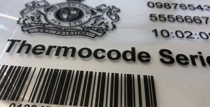 Auf einer weißen Verpackung sind ein detailreiches Wappen, Artikelnummern, Zeitstempel und Barcode in verschiedenen Schriftgrößen schwarz aufgedruckt.