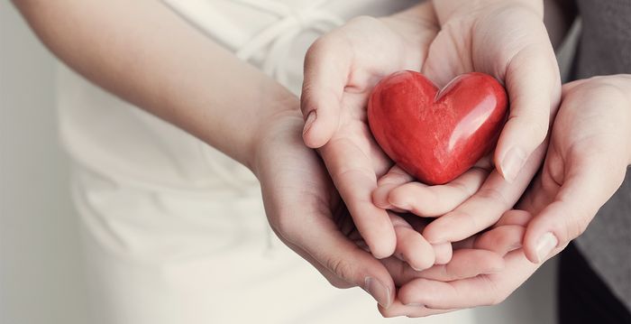 Die Hände von verschiedenen Personen liegen übereinander mit einem Herzen in der Mitte.
