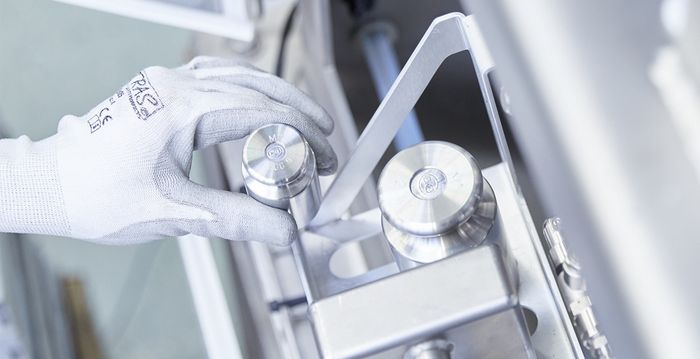 Eine Person mit Handschuhen hält ein Gewicht in der Hand.