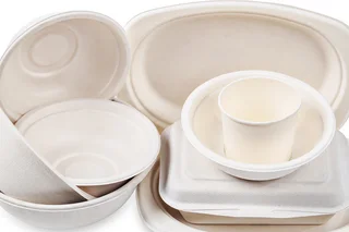 White disposable packaging made from paper pulp, various trays, cups and boxes stacked in an environmentally friendly manner on a white background.