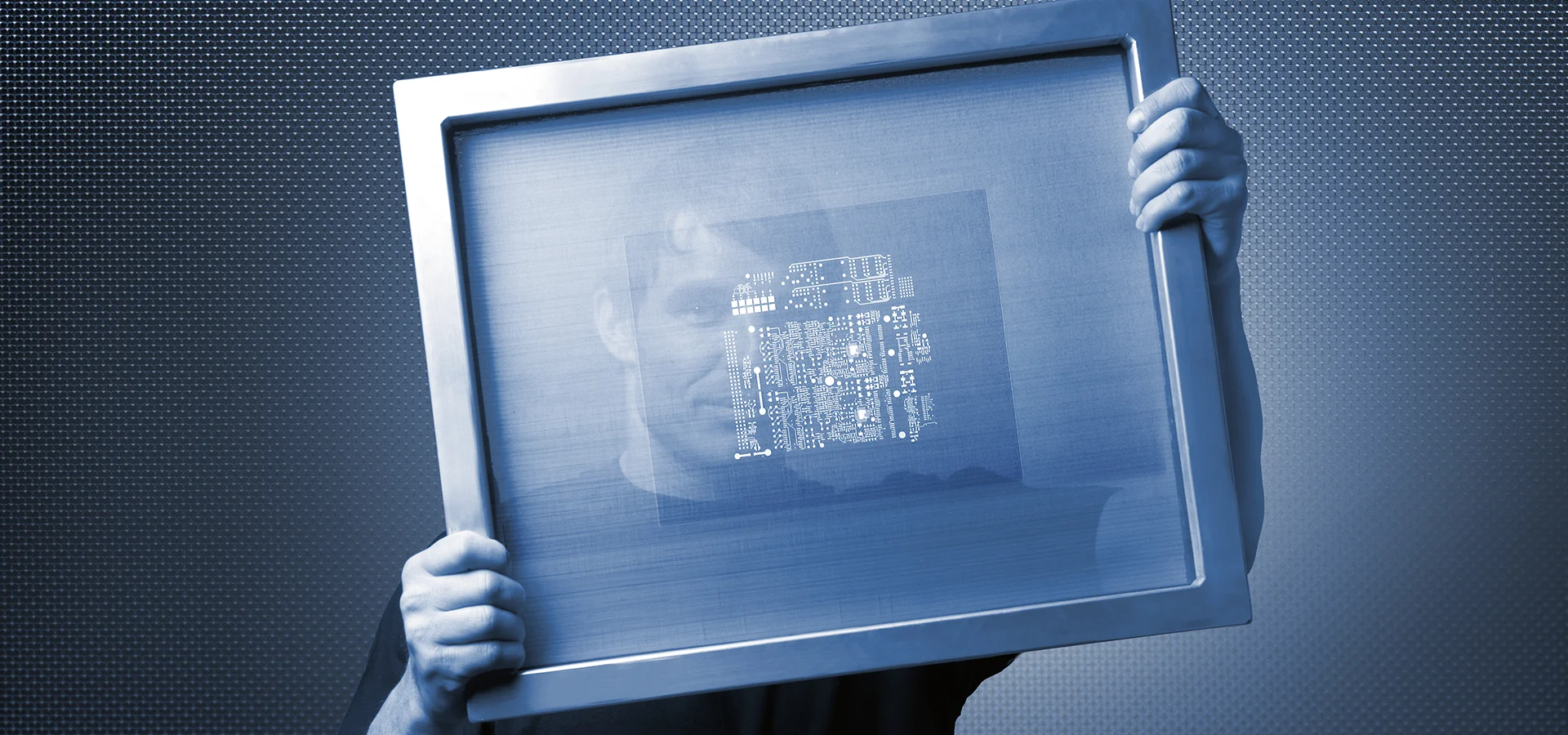 A man looks through a coated screen printing stencil.