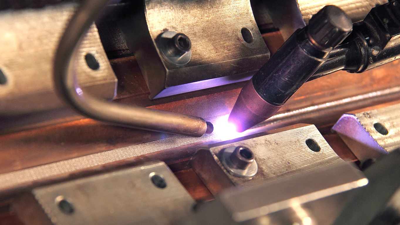 Schweißprozess mit Lichtbogen und Präzisionswerkzeugen bei Haver & Boecker zur Verbindung von Drahtgeweben in automatisierter Fertigung.