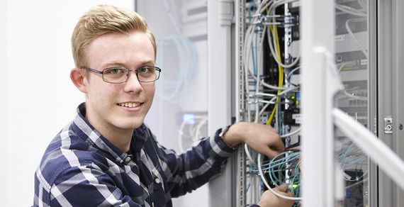 Ein Auszubildender steht am Schaltschrank.