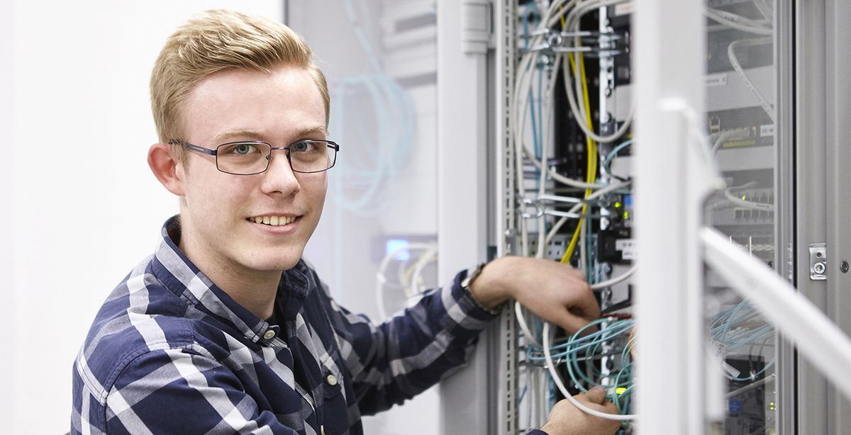 Ein Auszubildender steht am Schaltschrank.