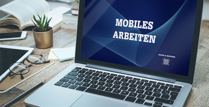 Ein aufgeklappter Laptop zeigt die Worte "Mobiles Arbeiten" an.