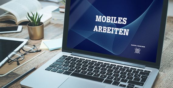 Ein aufgeklappter Laptop zeigt die Worte "Mobiles Arbeiten" an.