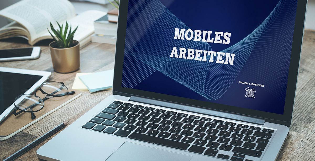 Ein aufgeklappter Laptop zeigt die Worte "Mobiles Arbeiten" an.