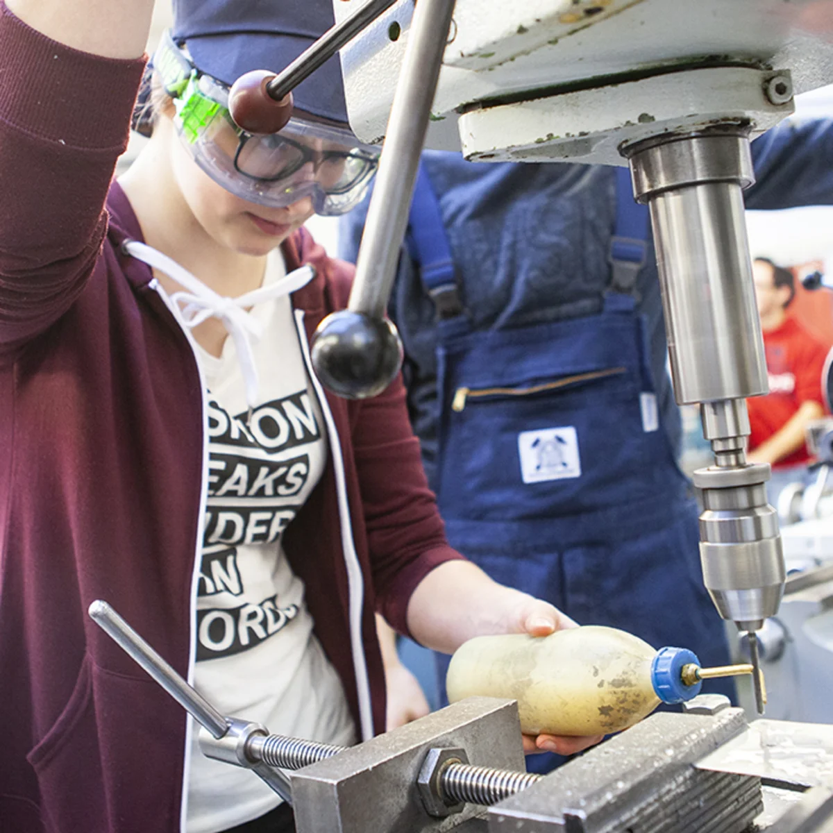 Ein junges Mädchen macht erste technische Erfahrungen an einer Maschine.