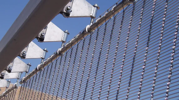 Fixation supérieure d’une façade en toile métallique avec des sangles de retenue au lieu d’une ossature continue.