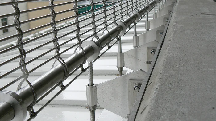 Sangles de retenue ponctuelles comme ossature d’un revêtement de façade en toile métallique.
