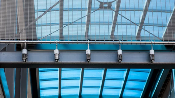 Revêtement de façade en toile métallique avec des sangles de retenue ponctuelles en guise d’ossature.