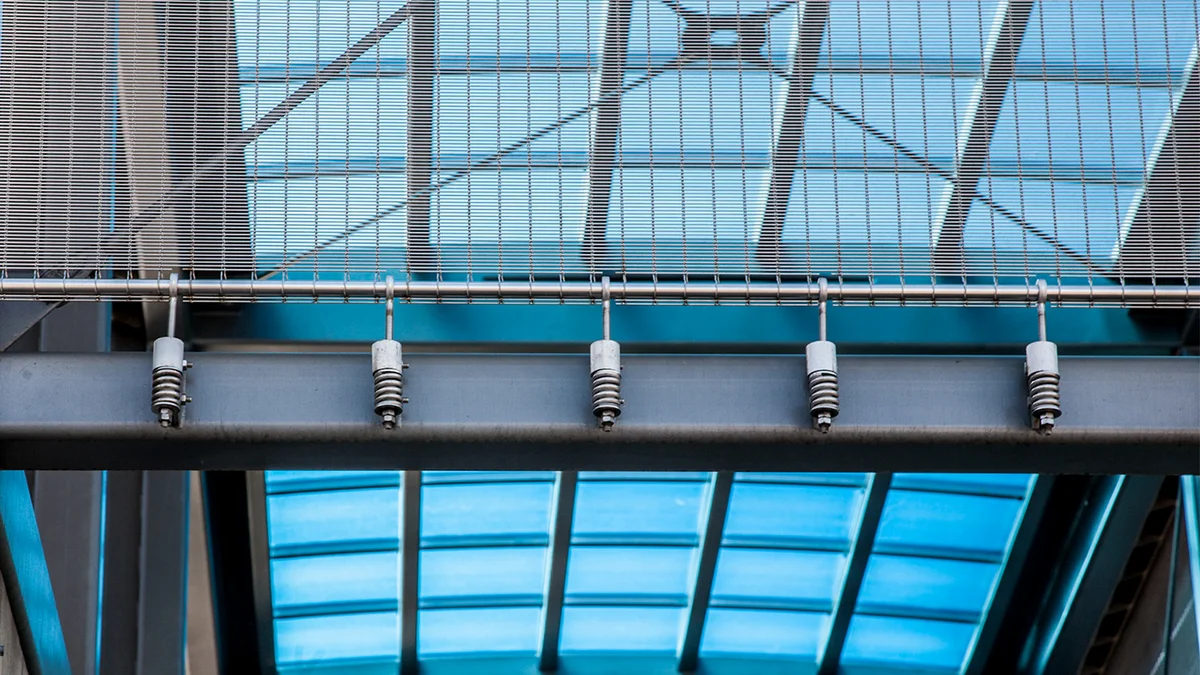 Revêtement de façade en toile métallique avec des sangles de retenue ponctuelles en guise d’ossature.