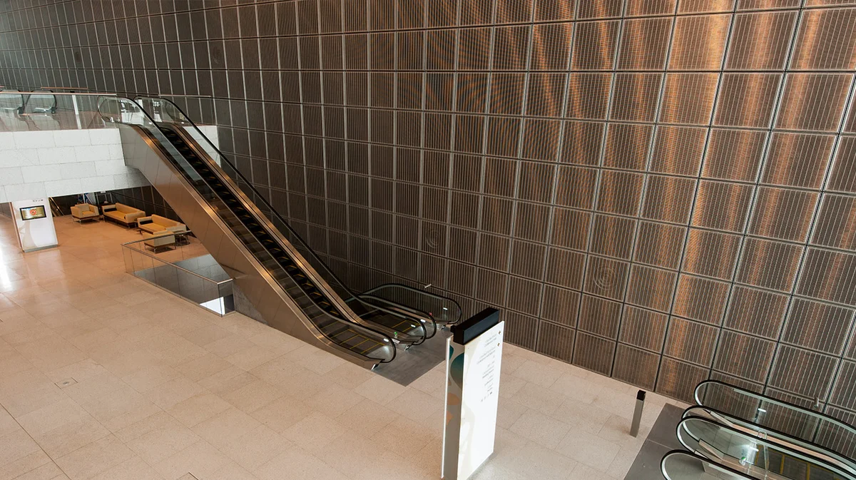 Shiny wall covering made out of quadratic frame elements with stainless steel wire mesh.
