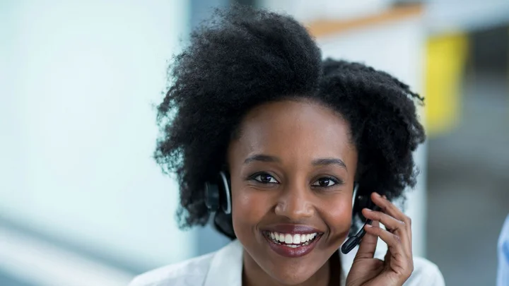 Eine Frau mit Headset nimmt einen Hotline-Anruf entgegen.