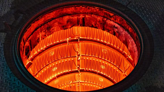 Vue intérieure d’une chambre de four industriel incandescente, avec des éléments chauffants rouge-orangé rayonnants à haute température.