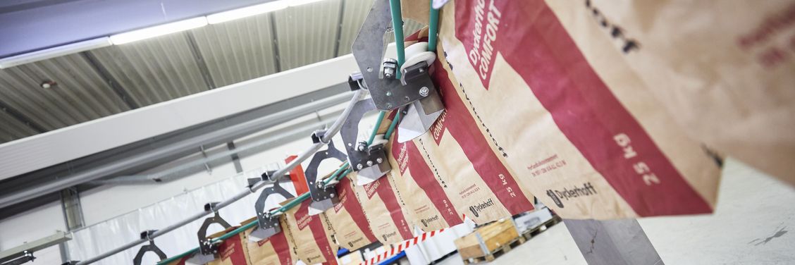 HAVER & BOECKER PATHFINDER automated bag handling system transferring empty bags from RADIMAT to ROTO-PACKER in a fully automated packing line