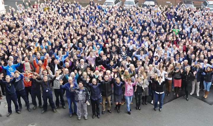 Ein Gruppenbild unserer Mitarbeiterinnen und Mitarbeiter winkend auf dem Hof.