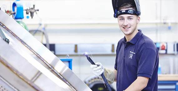 Ein angehender Industriemechaniker repariert eine Anlage der Drahtweberei.