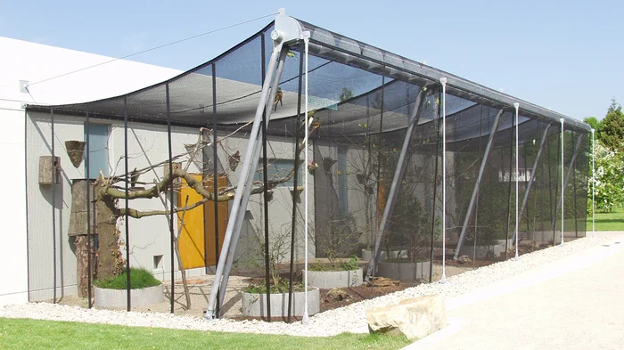 Volière en toile métallique peinte en noir.