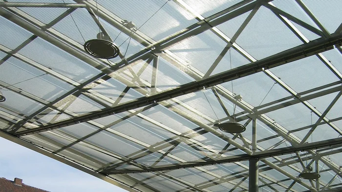 Ouvertures pour lampes dans les panneaux en toile métallique tendue d’un revêtement de plafond.