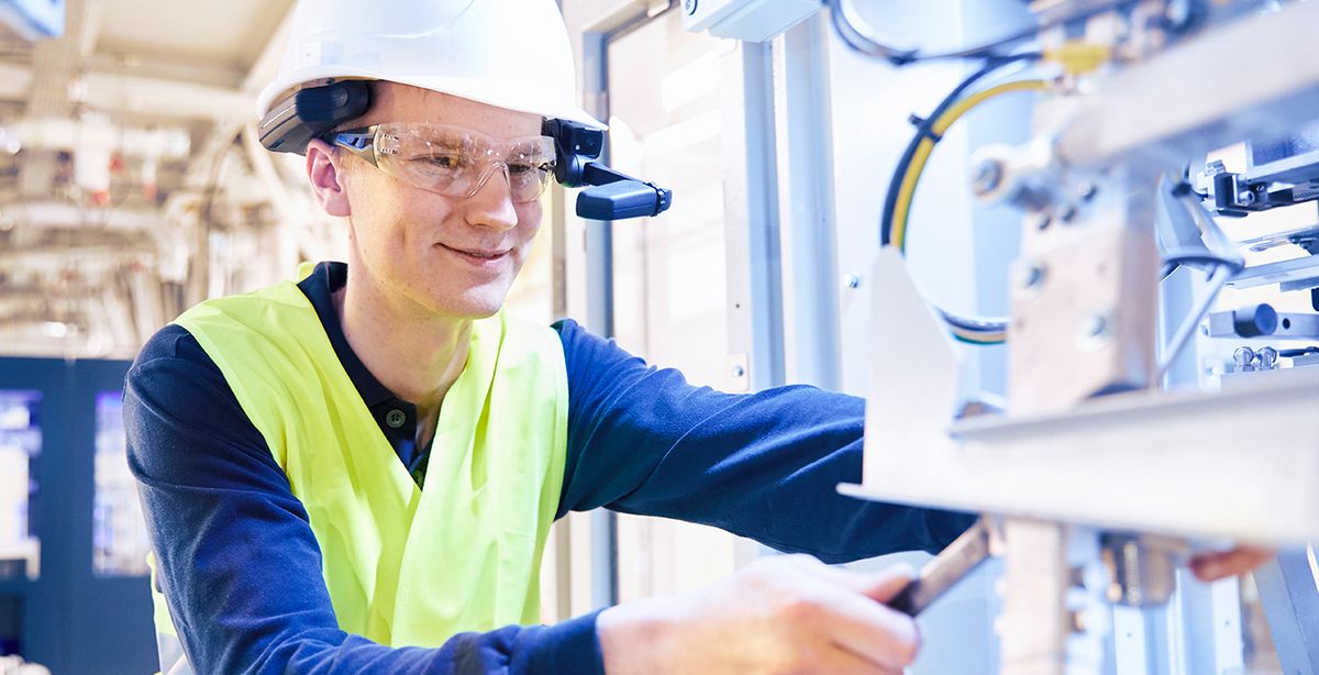Ein Mann mit einer intelligenter Brille arbeitet an einer Maschine.