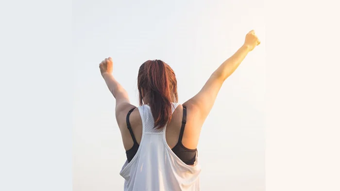 Symbolbild für erfolgreiche Prüfungsvorbereitung – Frau streckt jubelnd die Arme in die Luft