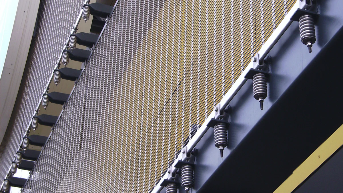 Sangles de retenue ponctuelles comme ossature d’un revêtement de façade en toile métallique.