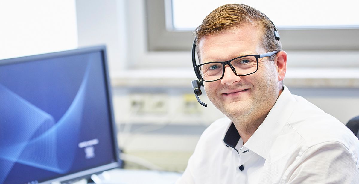 Ein Mann mit Headset nimmt einen Hotline-Anruf entgegen.