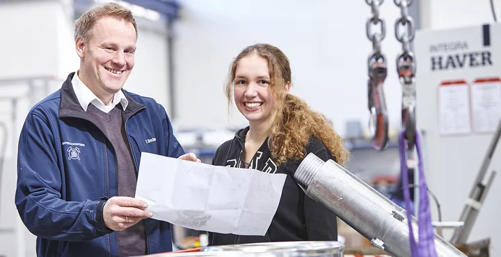 Ein Haver & Boecker Mitarbeiter zeigt einer Studentin etwas auf einem Plan. 