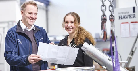 Ein Haver & Boecker Mitarbeiter zeigt einer Studentin etwas auf einem Plan. 
