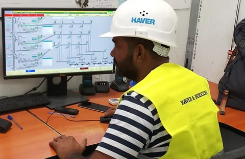 Ein Mann sitzt vor einem Bildschirm und überwacht den sicheren und effektiven Abfüllprozess.